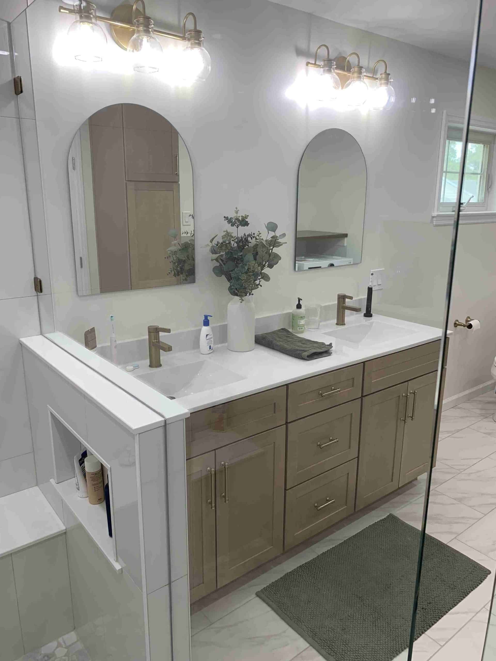 Modern bathroom with double vanity, quartz countertop, brass faucets, and arched mirrors