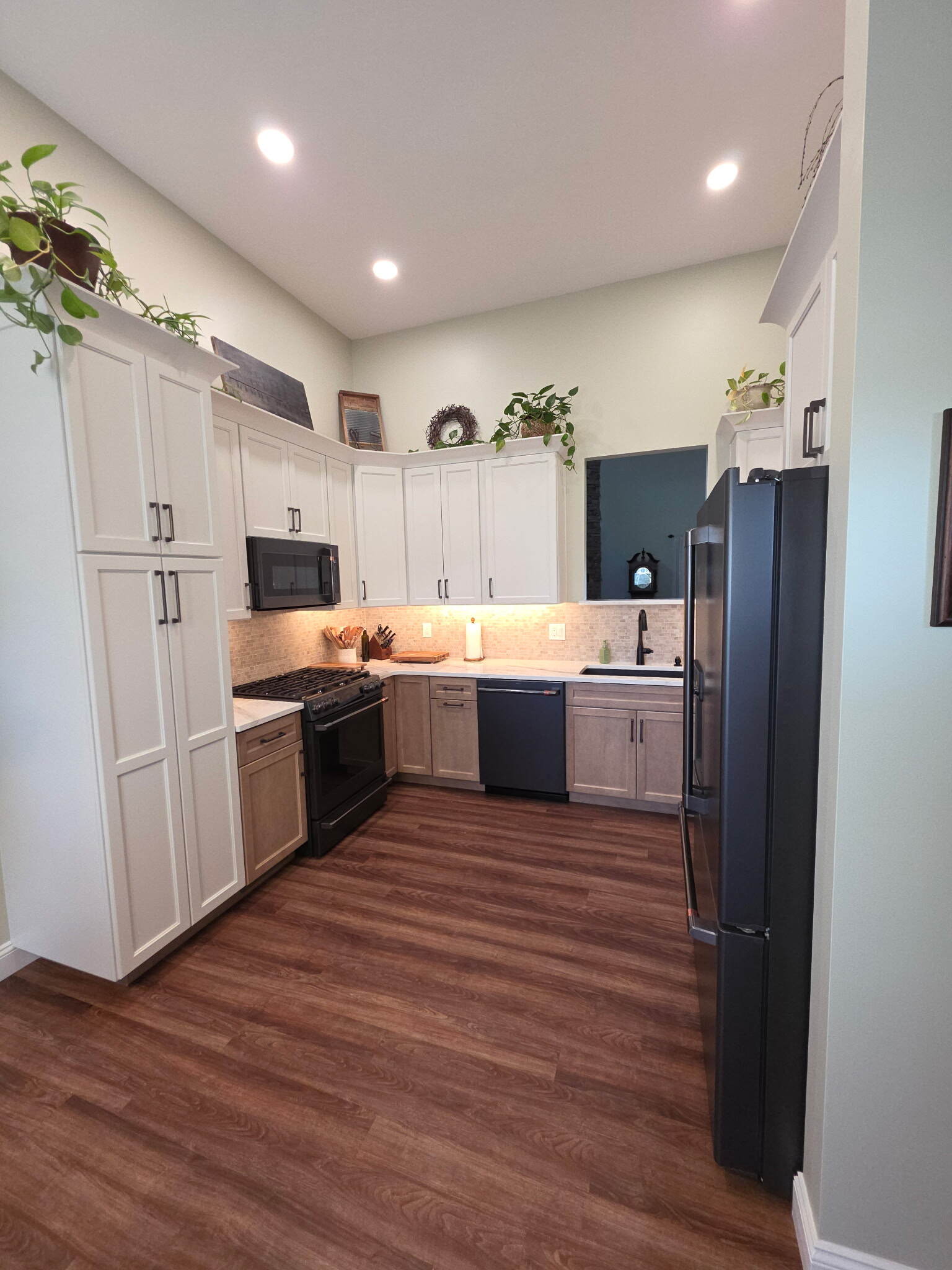 Modern L-shaped kitchen with two-tone cabinets and wood-look flooring
