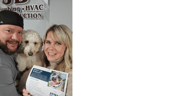Megan and Jeff, owners of JB Plumbing HVAC & Construction, holding their dog and the Berks ARL wishlist to promote the Thanksgiving pet supply drive.