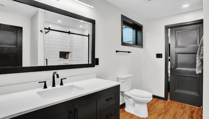 Modern bathroom remodel with black double vanity, white countertop, and large mirror