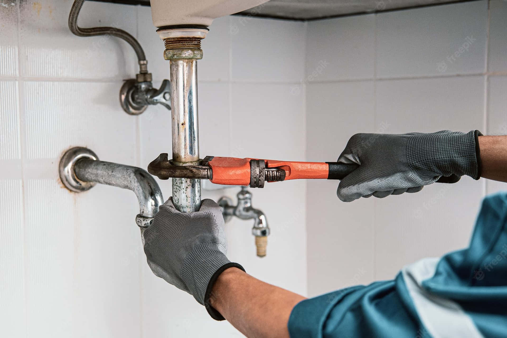 Professional plumber repairing sink drain with wrench Plumber using a pipe wrench to tighten a sink drain pipe connection