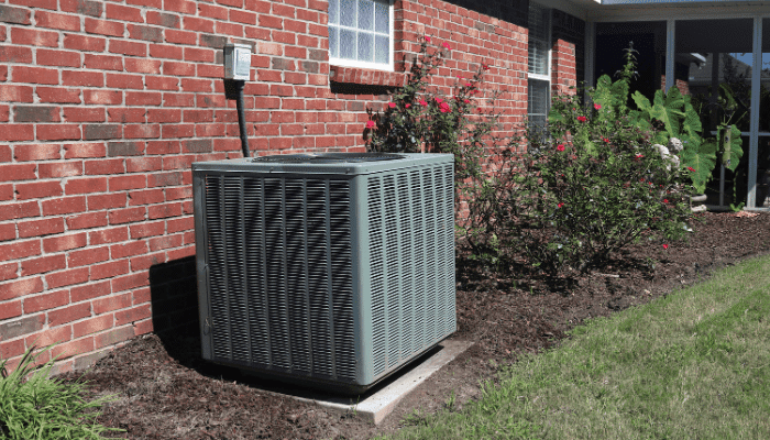 Outdoor AC condenser unit next to a brick home in Berks County, PA ready for spring maintenance